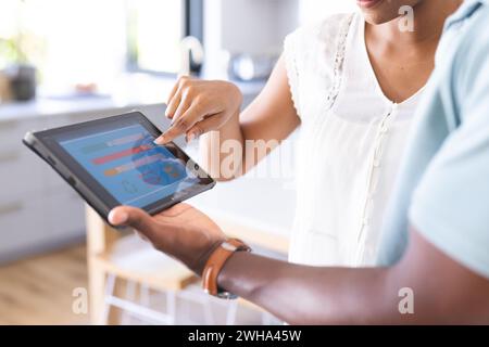 A young African American man and a biracial woman are using a tablet with a smart home app Stock Photo