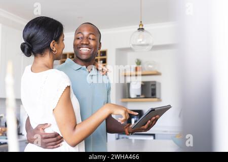 Biracial couple sharing a tablet at home, with copy space Stock Photo