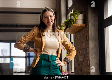 Young Caucasian woman poses confidently in a casual business setting in a modern office Stock Photo
