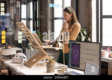 Young Caucasian woman works at a standing desk in a casual business office Stock Photo