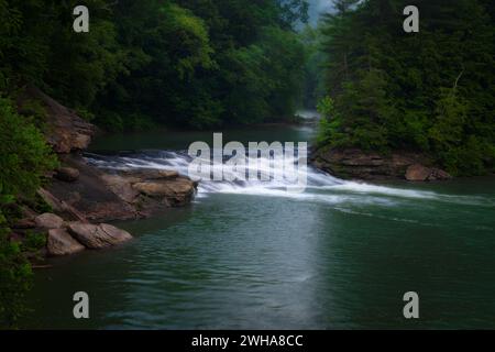 A small waterfall breaking up the peaceful winding river in West Virginia Stock Photo
