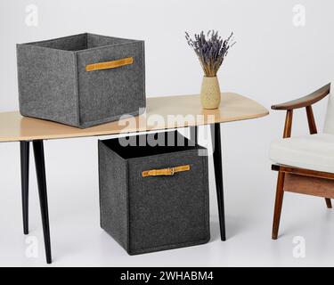 Two grey felt storage boxes and vase of lavender on desk Stock Photo