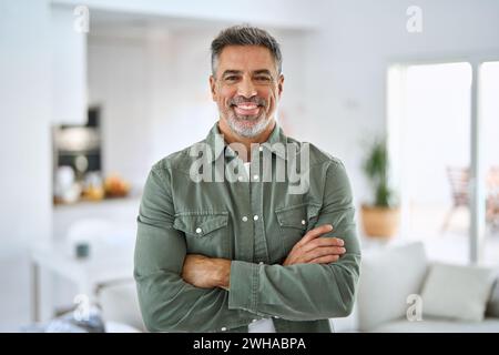 Happy middle aged senior man standing with arms crossed at home. Portrait. Stock Photo