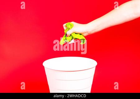 Throw napkin in trash bin, house cleaning rag in hand in front of trash can, cleaning concept Stock Photo