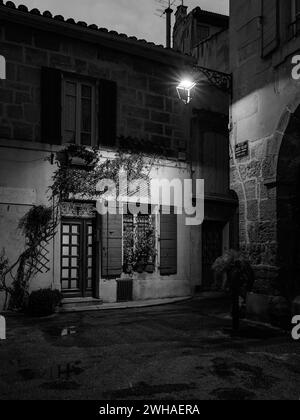 Arles, France - March 7, 2023: Empty street in the center of Arles (France) in the night, black and white, streetlamp over entrance of an old house Stock Photo