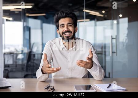 Cheerful Indian businessman working in a modern office, displaying confidence and approachability while dressed smartly. Stock Photo