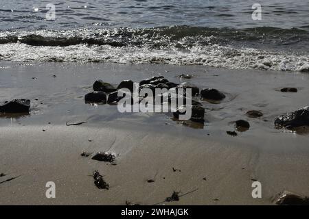 A scenic view of rocks on a sandy beach by the ocean Stock Photo