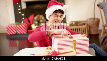 Young biracial man wrapping gifts at home, with copy space Stock Photo