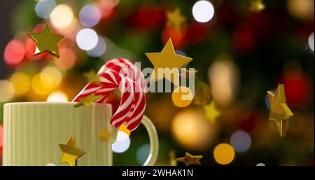 Image of gold stars christmas decorations over mug with candy canes background Stock Photo