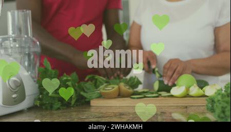 Image of hearts over senior african american couple cooking Stock Photo