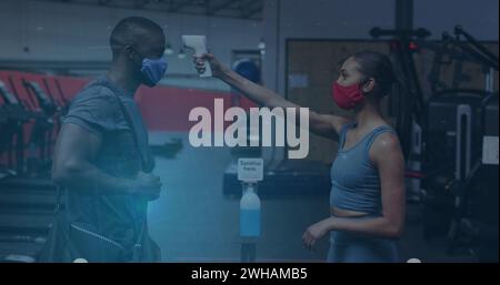 Coronavirus statistical data processing against woman measuring temperature of man at the gym Stock Photo