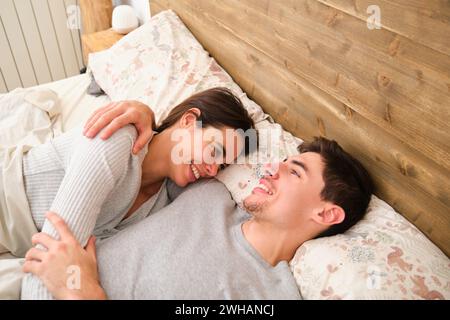 Spanish couple smiling while lying on bed in the morning. Stock Photo