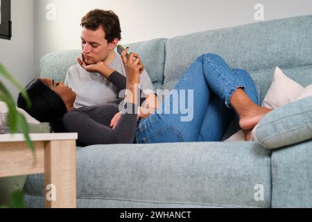Multiethnic romantic couple resting on a sofa at home. Stock Photo