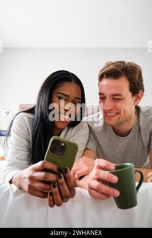 Multiethnic couple laughing while watching videos on the smartphone. Stock Photo