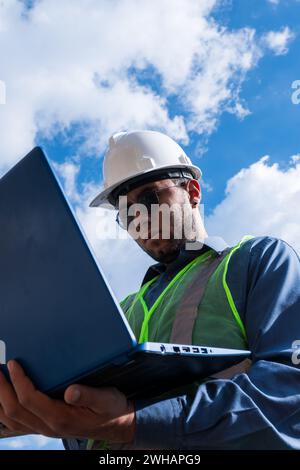 Engineer man working and looking laptop in sunny day Stock Photo