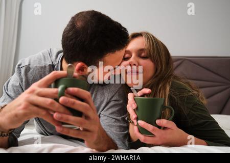 Spanish couple in love drinking coffee on bed. Stock Photo