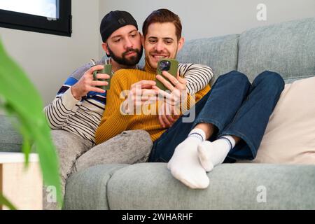 Homosexual couple lying on the sofa and using the phone together. Stock Photo