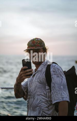 Man traveler with backpack in tourist place takes pictures on phone. Stock Photo