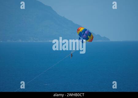 Single person paragliding from boat at beau vallon beach, Mahe, Seychelles Stock Photo