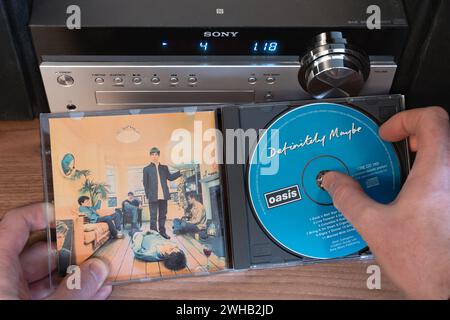 Definitely Maybe was released in August 1994 by Oasis. It was the fastest selling debut album ever (at the time). Hand removing CD from jewel case Stock Photo