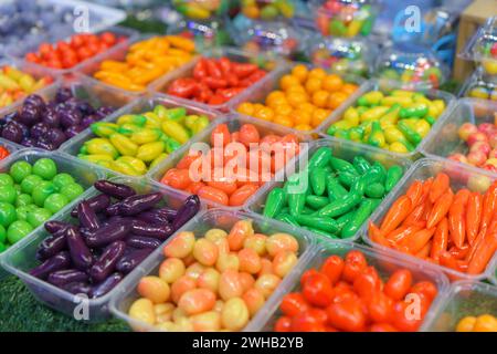 An assortment of Fruit Shaped Mung Beans vibrant Thai desserts, designed to resemble miniature fruits and vegetables, displayed in clear containers at Stock Photo