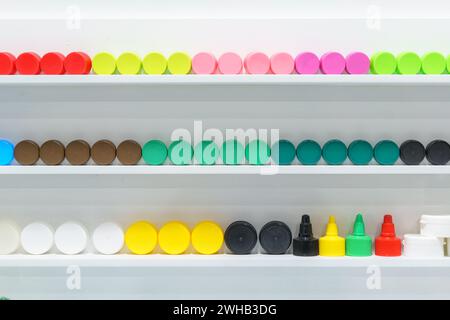 A vibrant collection of colorful bottle caps neatly organized on shelves, displaying a wide range of hues and sizes for packaging design inspiration Stock Photo