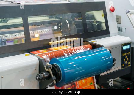 High-resolution image depicting the industrial printing process of adhesive labels, showcasing the machinery and label sheet emerging with vibrant red Stock Photo