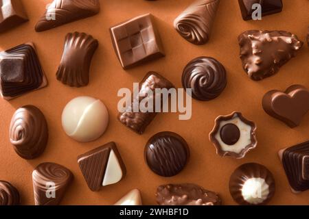 Assortment of chocolate bonbons on a brown background. Top view. Stock Photo