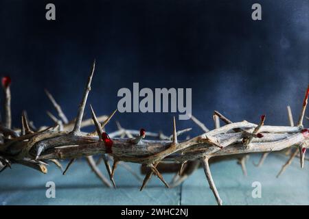 Dark Christian crown of thorns like Jesus Christ wore with blood drops over a rustic wood background or table. Selective focus with blurred background. Stock Photo