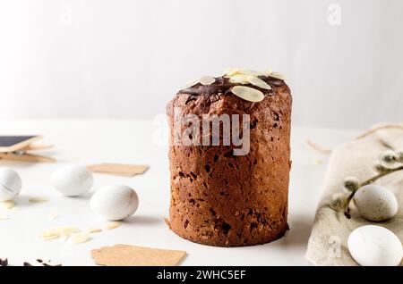 Place setting for Easter dinner on the white table with Easter cake with colorful topping, Decorative chocolate eggs sweets, willow and holiday decora Stock Photo