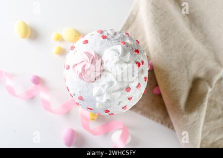 Place setting for Easter dinner on the white table with Easter cake with colorful topping, Decorative chocolate eggs sweets, willow and holiday decora Stock Photo