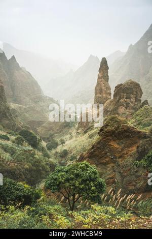 Mountain peaks of Xo-Xo valley of Santa Antao island, Cape Verde. Many cultivated plants growing in the valley between high rocks. Arid and erosion mountain peaks sun light. Sahara dust in the air. Stock Photo