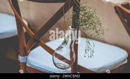 Original wedding floral decoration in the form of mini-vases and bouquets of flowers hanging from the chair Stock Photo