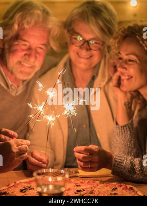 group of people and family celebrating some party or new year together at the terrace of the home - four sparklers at the middle together Stock Photo