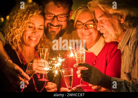 group of two seniors and two adults together having fun with sparlers the new year to celebrate - happy family with lights Stock Photo