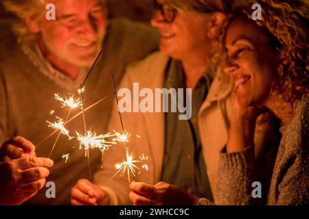 group of people and family celebrating some party or new year together at the terrace of the home - four sparklers at the middle together Stock Photo