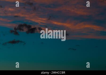 Beautiful cloudscape of blue sky with low pinkish colored cirrus clouds and a few scattered dark cumulus clouds Stock Photo