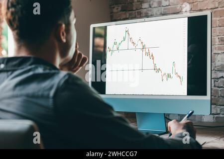 Caucasian business man trader investor analyst looking at financial stock market charts rate dynamic, trading data indexes growth using mobile phone and laptop for cryptocurrency digital analytics. Stock Photo