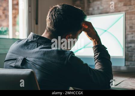 Stressed tired man in pain having strong terrible headache attack after computer laptop work, fatigued exhausted guy suffering from chronic migraine massaging temples to relieve head ache tension Stock Photo