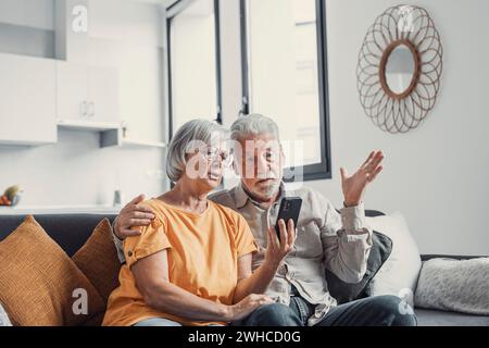 Shocked upset elderly couple getting bad news, finding fraud, money stealing, loss, overspending, financial problem, holding calculator, using phone, staring at monitor Stock Photo
