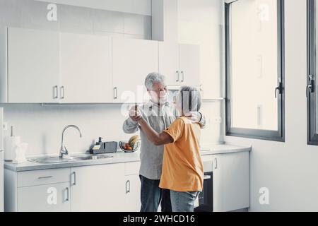 Joyful active old retired romantic couple dancing laughing in living room, happy middle aged wife and elder husband having fun at home, smiling senior family grandparents relaxing bonding together Stock Photo