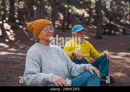 Portrait, close up of two old seniors middle age people meditating and relaxing in the mountain in the middle of the forest outdoors. Two mature persons having fun enjoying relax. Stock Photo