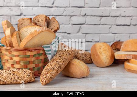 A woven bread basket filled with a selection of bread on a wooden table Stock Photo