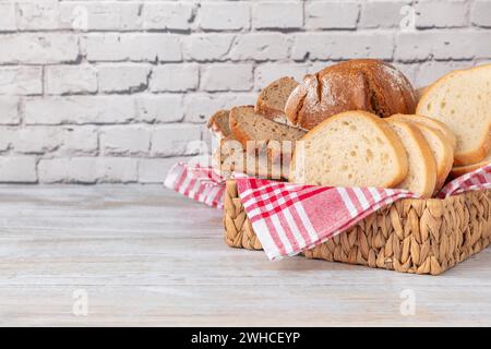 A basket with different types of bread on a brick wall, copy room Stock Photo