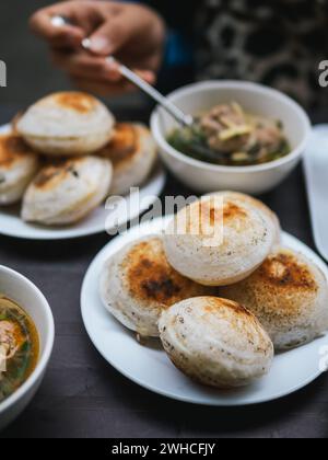 Banh can - The mini pancakes with rice flour, egg, onion leaves with soft selective focus, and blurred background. Banh can is a portion of Vietnamese Stock Photo