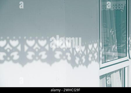 Sunlight shines through white wooden slats. Beautiful shadow on building wall. used for background and display your product. Stock Photo