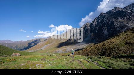 Mountaineers on a hiking trail, green high valley, Keldike Valley on the way to the Ala Kul Pass, Tien Shan Mountains, Kyrgyzstan Stock Photo