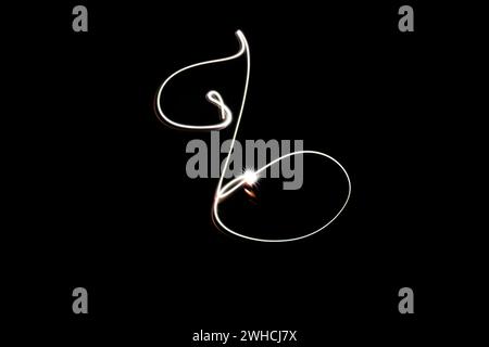 An elegant swirl of light creates a dynamic, abstract shape, dancing music key against a pure black background, capturing the art of light in motion. Stock Photo