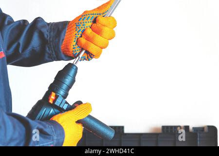 close-up. hands in protective gloves, hammer drill, installation of a chisel in a perforator. The concept of replacing the rotary drill. Stock Photo