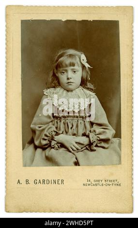 Original Victorian CDV  Carte de Visite ( visiting card or CDV)  of bored looking Victorian girl, hands in lap, studio of A.B . Gardiner 14 Grey Street, Newcastle on Tyne, Circa 1900 Stock Photo